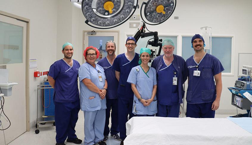 A group of healthcare professionals in scrubs standing together in a hospital room.
