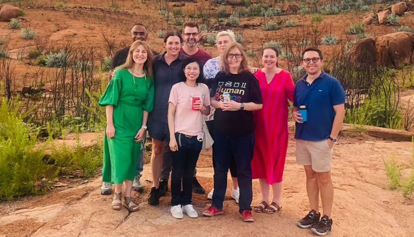 A group of people standing together on a rocky hillside, surrounded by natural scenery.