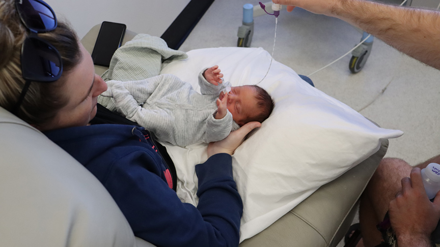 A woman cradles a newborn baby in her arms while resting in a hospital bed.
