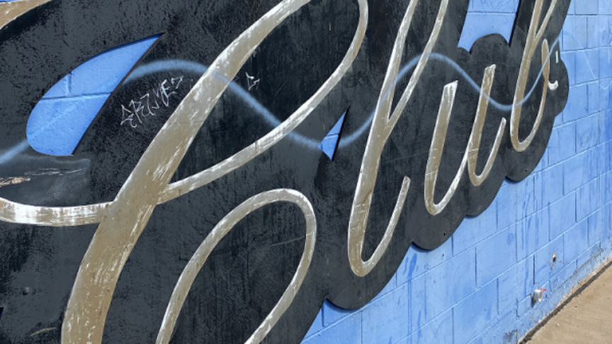 A club sign is prominently painted on the side of a building, showcasing its name and vibrant colors.